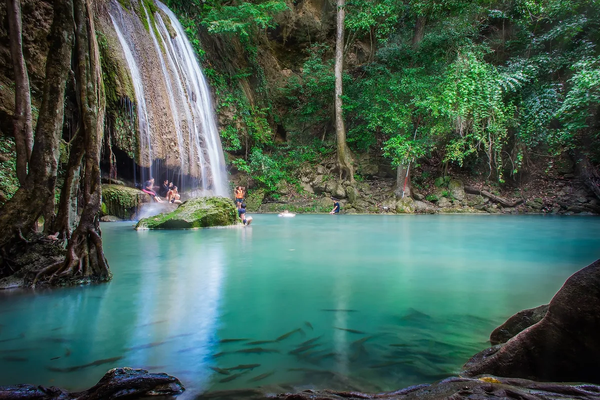 Visitors enjoying Erawan Waterfall surrounded by lush greenery in Kanchanaburi